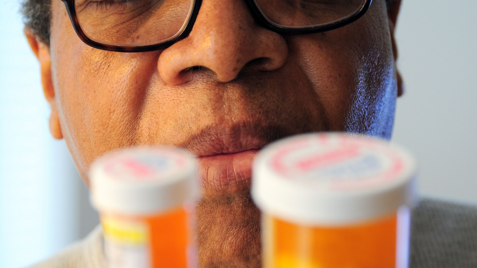 Older adult carefully reviewing two prescription bottles